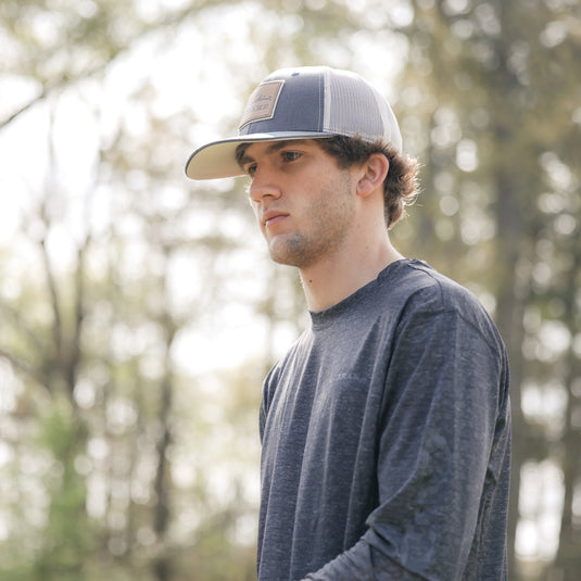 A man in a Performance Crew hat, showcasing UPF 50 sun protection, moisture-wicking, and quick-drying features. Ideal for hunting, fishing, and outdoor activities.