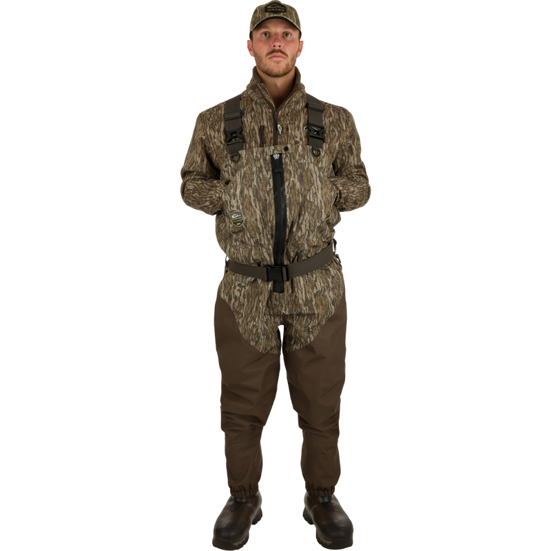 A man wearing Uninsulated Guardian Elite HND Front Zip Waders in Realtree camouflage, standing confidently in the outdoors.