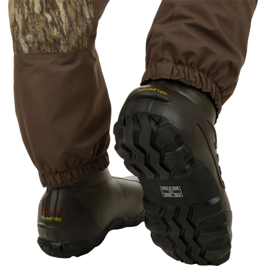 A pair of Youth Insulated Guardian Elite Vanguard Breathable Waders with camouflage patch and Thinsulate Buckshot Mudder boots.