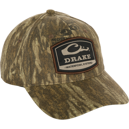 A 6-Panel Badge Cap with a patch on it, featuring a close-up of the patch and logo. Made of cotton blend panels with a rear snap closure. Perfect for outdoor enthusiasts.
