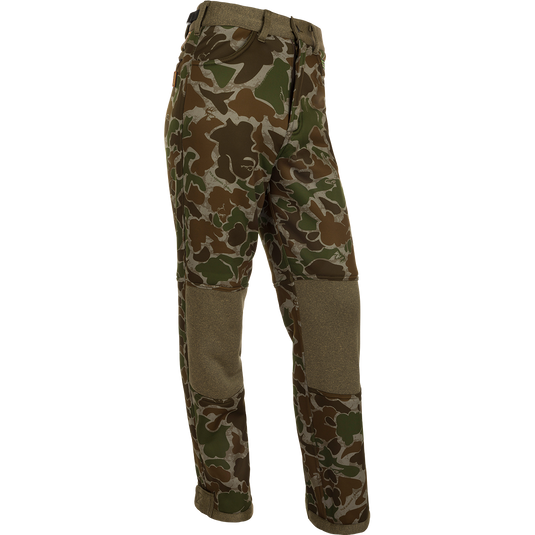 A pair of camouflage pants with Agion Active XL scent control technology, designed for Mid to Late Season deer stand hunting. Made of soft-shell fabric with a micro-fleece lining for warmth and comfort. Features adjustable waist, hook and loop ankle, and elastic foot stirrups. Perfect for big game hunting, waterfowl hunting, turkey hunting, and fishing.