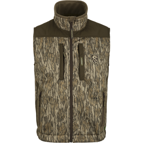 Standstill Windproof Vest with Agion Active XL®: A camouflage jacket with a logo of a deer, perfect for mid-to-late season hunting. Features include scent control technology, zippered pockets, and a safety harness pass-through opening. Ideal for layering or wearing over a mid-layer.