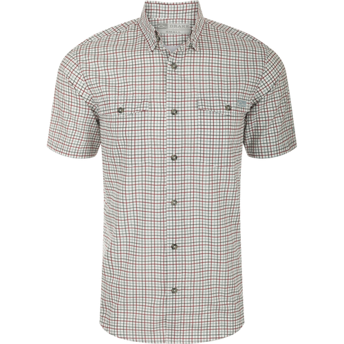 A close-up of the Drake Frat Tattersall Shirt, featuring a white and red plaid pattern. The lightweight performance fabric offers UPF30 sun protection, moisture-wicking, and quick-drying properties. With a classic fit and hidden button-down collar, it also includes two button-through flap chest pockets, a vented cape back, and a sculpted hem. The shirt even has a built-in sunglass wipe. Perfect for big game hunting, waterfowl hunting, turkey hunting, fishing, and casual wear.