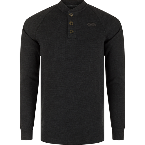A black long sleeve Henley shirt with metal logo buttons, raglan sleeves, rib knit collar, and cuffs. Made of waffle mélange fabric for comfort, antimicrobial, and moisture-wicking properties. Split tail hem for versatile styling.