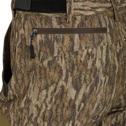 A close-up of the EST Camo Tech Stretch Pant, made from lightweight polyester. Features include adjustable waistband, multiple pockets, and elastic ankle cinch cord. Ideal for hunting and outdoor activities.