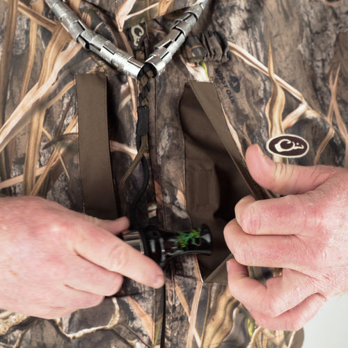 A close-up of a man's hands opening a pocket on the EST Heat-Escape Full Zip 2.0 - Realtree jacket, showcasing its practical features for early season use.