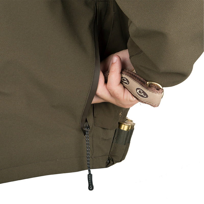 A person holding the Guardian Elite Flooded Timber Insulated Jacket, designed for hunters. Features include waterproof fabric, body-mapped insulation, and multiple pockets for calls and shells.