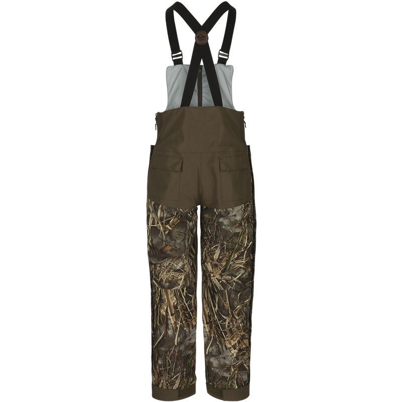 A product image of the EST Guardian Elite™ Bib Shell Weight, perfect for hunters needing protection from the elements. The Guardian Elite™ Bib Shell Weight offers full-body cover-up with waterproof/windproof/breathable fabric. Featuring reinforced knees, adjustable shoulder straps, and multiple pockets.