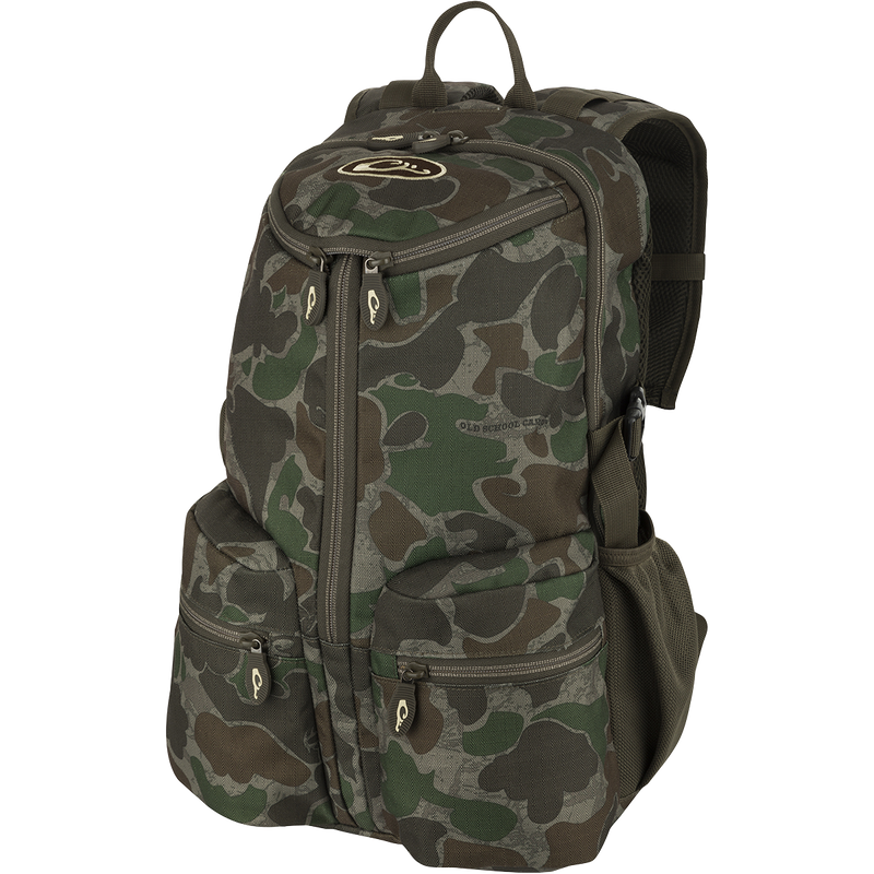 A compact and functional Vertical Zip Daypack, perfect for hunting or everyday use. Features include padded shoulder straps, large interior storage, external carry straps, and hydration bladder compartment. Made with 100% Polyester Rugged HD2™ Material and Drake’s Fowl-Proof™ YKK Zippers. Dimensions: 18.5
