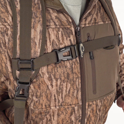 A person wearing a camouflage Swamp Sole Backpack with multiple storage pockets and shell loops for hunting gear.