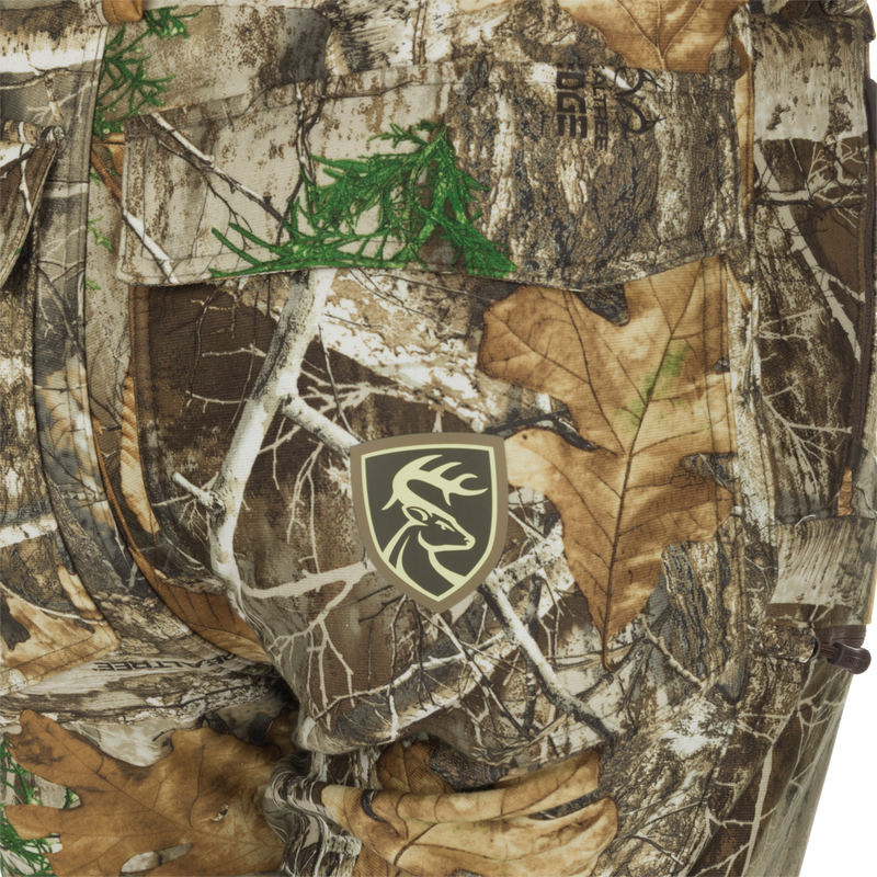 MST Microfleece Softshell Pant: Close-up of camouflage pants with deer logo. Wind-resistant, moisture-repellent, and scent-controlled. Comfortable fit with articulated knees and side zips for easy movement.