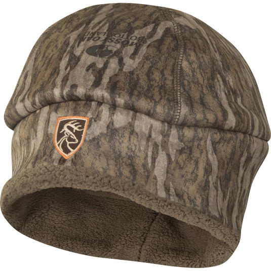 A camo Non-Typical Silencer Sherpa Fleece Beanie with Agion Active XL® for hunting, featuring a deer logo patch. Deep cut for ear protection, scent control technology.