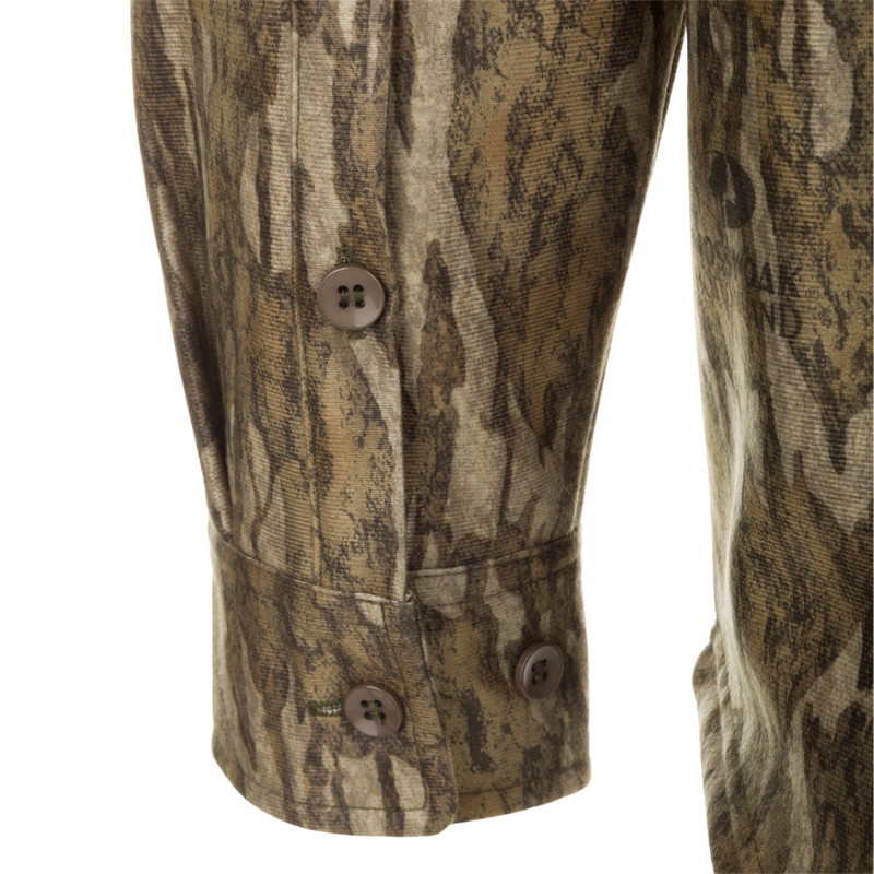 A close-up of the MST Microfleece Softshell Shirt, featuring a camouflage pattern. Made of wind-resistant softshell fabric with a microfleece lining and DWR treatment. Includes scent control technology, 7-button placket, gusseted underarm, 4-way stretch, and convenient pockets.