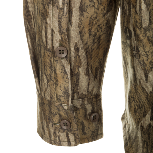 A close-up of the MST Microfleece Softshell Shirt, featuring a camouflage pattern. Made of wind-resistant softshell fabric with a microfleece lining and DWR treatment. Includes scent control technology, 7-button placket, gusseted underarm, 4-way stretch, and convenient pockets.