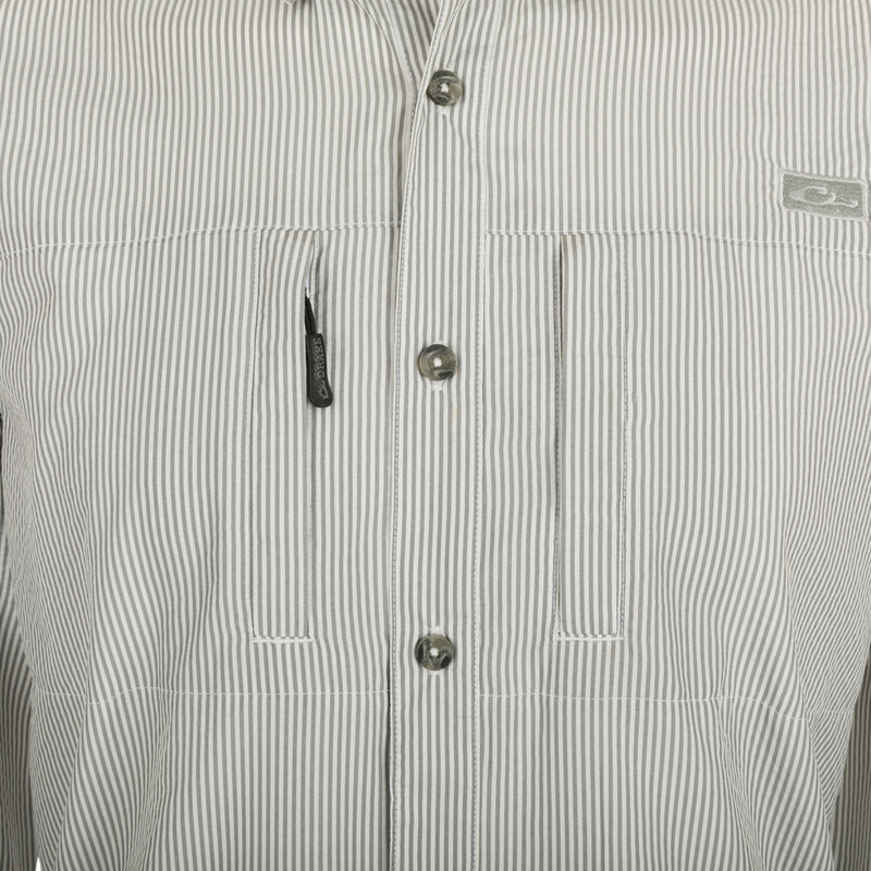 A close-up of the Drake Classic Seersucker Stripe Shirt, featuring a button-down collar, hidden zippered chest pocket, and Magnattach™ closure. Made from 72% Polyester and 28% Nylon, this soft and featherweight shirt offers UPF30 sun protection and moisture-wicking properties. With a vented cape back and split tail hem, it provides comfort and versatility. Perfect for big game hunting, waterfowl hunting, turkey hunting, and fishing.
