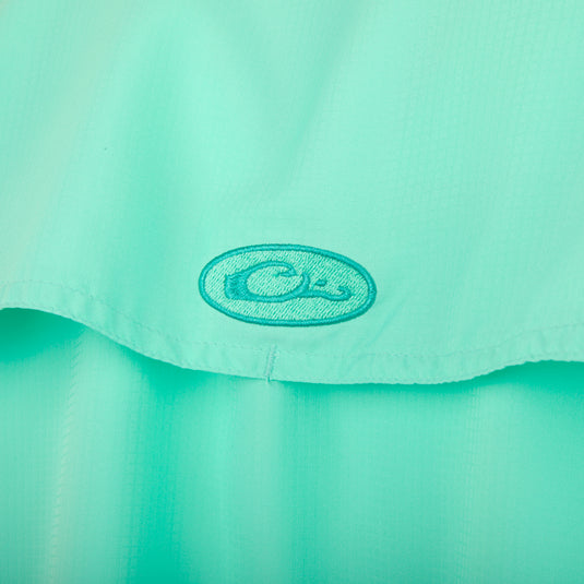 A close-up of the aqua Flyweight Shirt with Vented Back L/S logo, showcasing its lightweight and breathable design for warm-weather outdoor activities. Made of quick-drying, moisture-wicking polyester with UPF 50+ sun protection. Features include a vented mesh back, horizontal chest pockets, hidden button downs, and a locker loop.