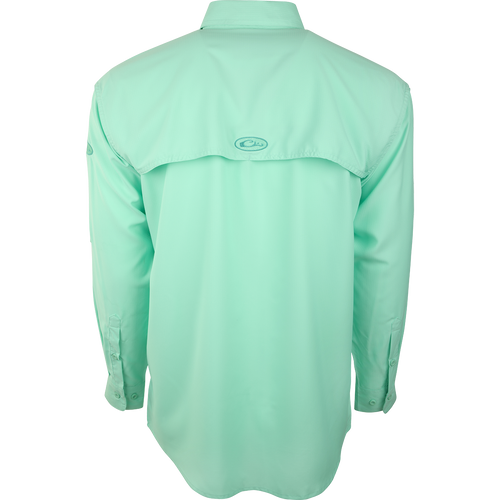 A close-up of the Flyweight Shirt with Vented Back L/S, a green shirt with a logo. Designed for warm-weather outdoor activities, it's made of ultra-lightweight polyester with UPF 50+ sun protection. Quick-drying, moisture-wicking, and breathable, it features a vented mesh back and horizontal chest pockets. Perfect for hunting, fishing, and other outdoor adventures.
