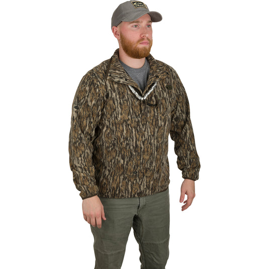 A man wearing a camouflage jacket and hat, showcasing the MST Camo Camp Fleece ¼ Placket Pullover for outdoor activities.