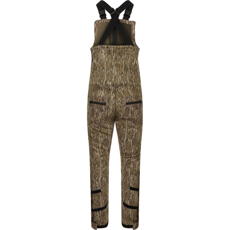 A brown overalls with black straps, featuring a four-way stretch material, gusseted crotch, and articulated knees for ease of movement. Includes Sherpa-lined slash handwarmer pockets, Magnattach™ left chest pocket, and zippered rear security pockets. MST Ultimate Wader Bib.