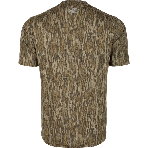 Youth EST Camo Performance Short Sleeve Crew, a back of a shirt with a logo close-up. Ideal for outdoor activities with 4-Way Stretch, Shield 4 Sun™ UPF 50+, Shield 4 Coolant™, Shield 4 Odor™, and Shield 4 Stains™ treatments.
