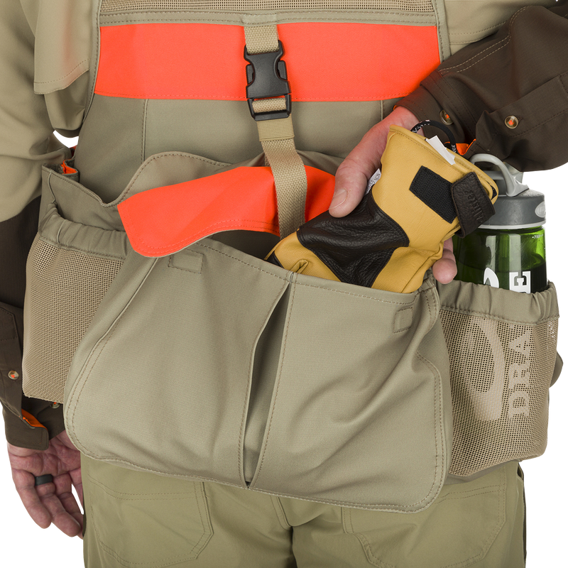 McAlister Upland Strap Vest: Person wearing a tool belt with rugged interior hip belt and seamless shoulder straps. Large cargo pockets and expandable game bag for easy access.