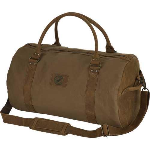McAlister Leather & Waxed Canvas Duffel Bag: A rugged brown bag with straps, made of top grain water buffalo leather and premium waxed cotton fabric. Features brass hardware, leather shoulder strap, rolled handles, and a 40L capacity. Perfect for hunting gear and outdoor adventures.