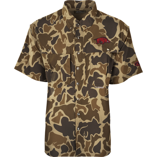 Arkansas S/S Flyweight Wingshooter: A camouflage shirt with a red pig, featuring quick-drying, moisture-wicking fabric, UPF 50+ sun protection, vented back design, and multiple pockets. Ideal for warm-weather outdoor activities.