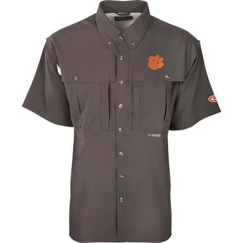 Clemson S/S Flyweight Wingshooter: A grey shirt with an orange logo and tiger paw patch. Made of ultra-lightweight polyester for quick-drying and breathability. Features include UPF 50+ sun protection, vented back design, Magnattach™ chest pocket, and vertical zipper pocket. Ideal for warm-weather outdoor activities.