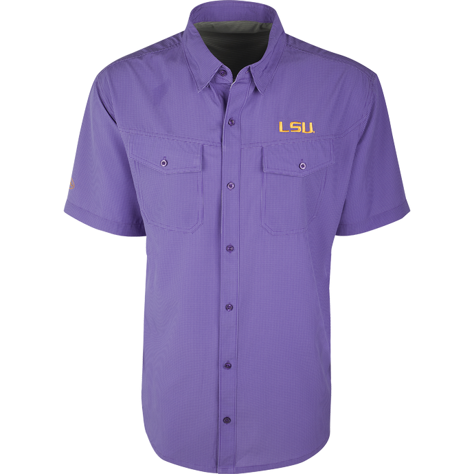 LSU S/S Traveler's Shirt, a purple button-up with a yellow logo. Lightweight, breathable fabric with four-way stretch for comfort. Ideal for football games or weekend tailgates. Moisture-wicking with 2 chest pockets.