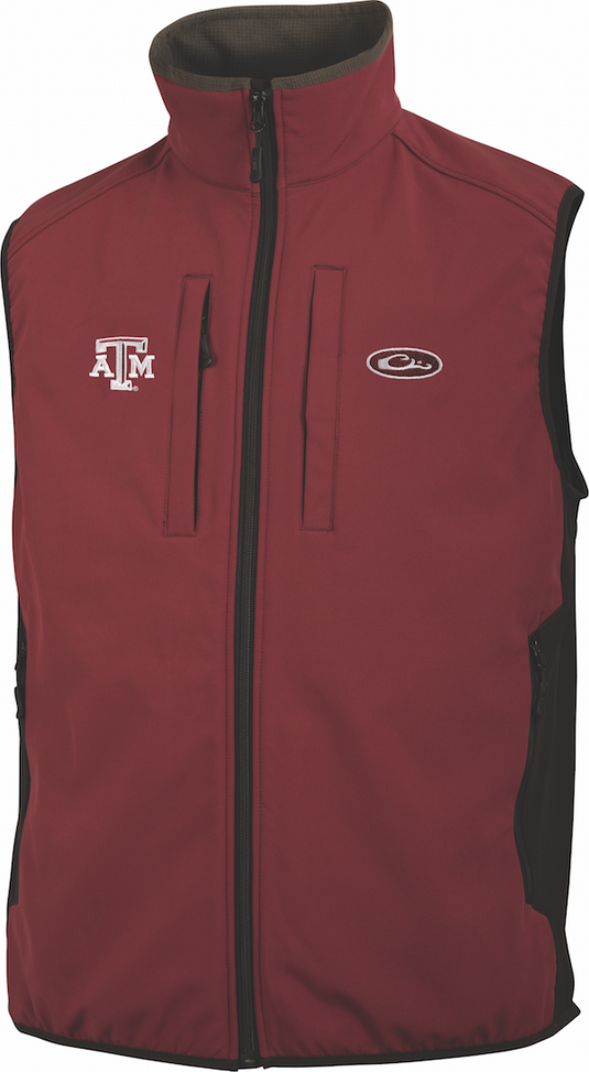Texas A&M Windproof Tech Vest: Red vest with logo, featuring vertical Magnattach chest pocket, zippered chest pocket, lower zippered pockets, drawstring waist, and side stretch panels. Made of 100% polyester with bonded fleece lining. Ideal for hunting and outdoor activities.