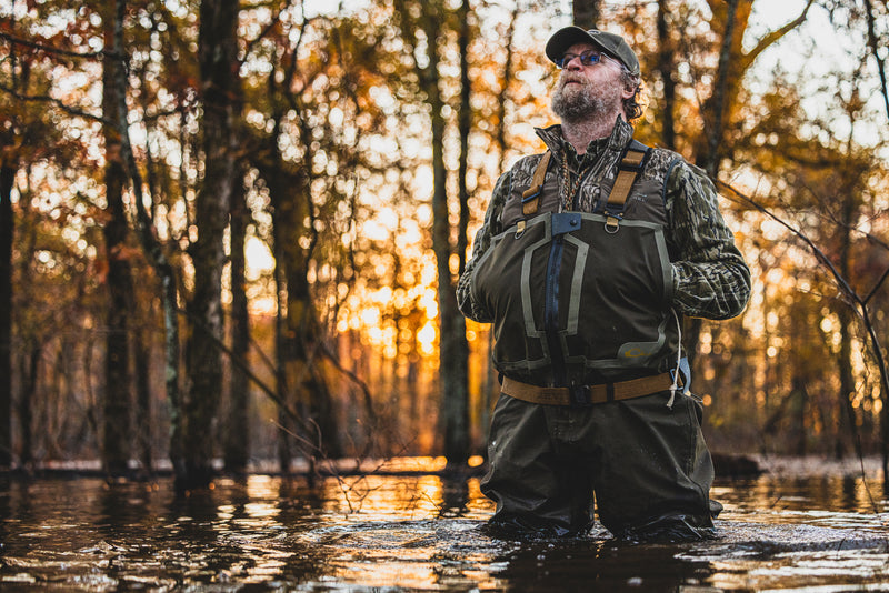 Man in flooded forest wearing LST BMF Vest with Primaloft, showcasing its water resistance and windproof features, ideal for versatile hunting and outdoor activities.