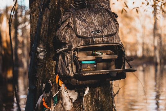 Tree Hugger Timber Pack with camo pattern, open to show Waterfowl shotgun shells, shotgun, and harvested ducks, demonstrating its rugged design and ample hunter storage features.