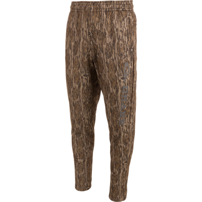 Drake Under-Wader Jogger with camouflage pattern, featuring front slash pockets, hook and loop closure rear pockets, and tapered legs for secure fit under waders.