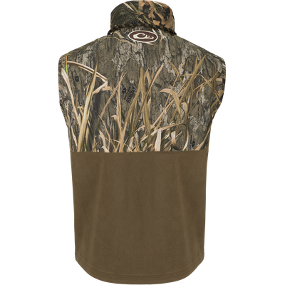 Back view of MST Eqwader Vest - Habitat featuring Mossy Oak camouflage and solid brown fleece, with logo at nape, highlighting outdoor functionality and storage pockets.