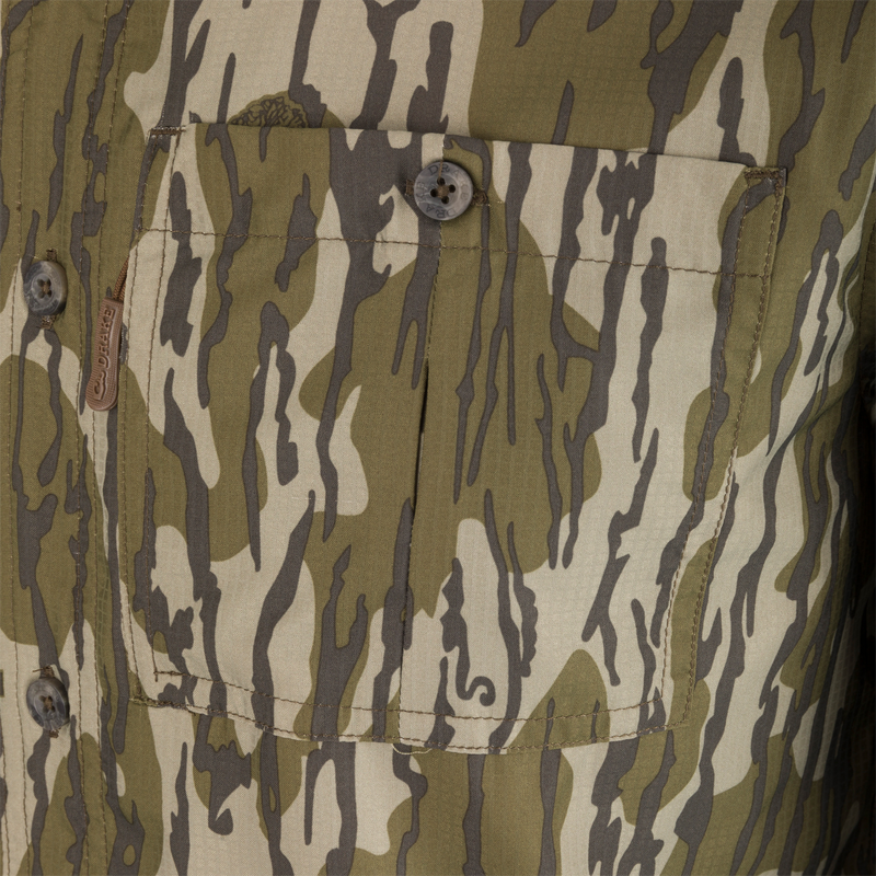 Close-up of the Ole Miss 8-Shot Long Sleeve Shirt's camo-patterned front pocket, showcasing the button closure and leather branding tab DRAKES.