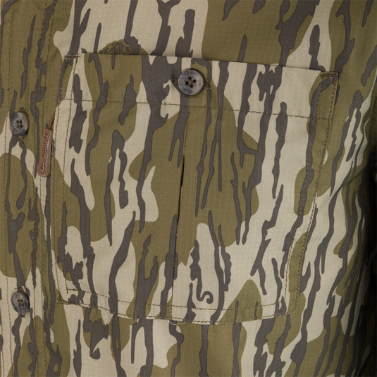 Close-up of the Ole Miss 8-Shot Long Sleeve Shirt's camo-patterned front pocket, showcasing the button closure and leather branding tab DRAKES.