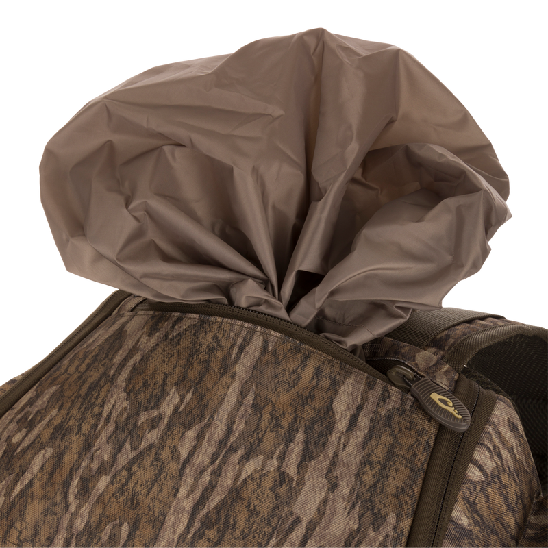 Camouflage-patterned Tree Hugger Timber Pack with partially exposed brown rain cover, showcasing rugged construction, multiple pockets, and ergonomic design for hunting gear organization.