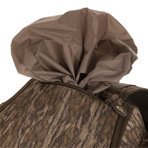 Camouflage-patterned Tree Hugger Timber Pack with partially exposed brown rain cover, showcasing rugged construction, multiple pockets, and ergonomic design for hunting gear organization.