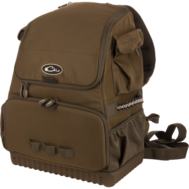 Tree Hugger Timber Pack, a rugged olive-green daypack with a flap top, front zippered pocket, side mesh pouch, padded straps, and paracord detailing.