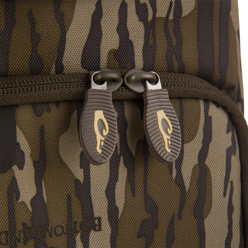 Close-up of Tree Hugger Timber Day Pack's camouflage fabric with brown zipper sliders, showcasing the rugged design for outdoor excursions.