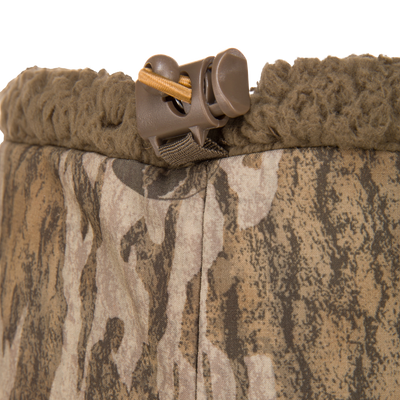 Close-up of LST BMF Gaiter with Primaloft, showcasing woodland camo shell, soft fleece lining, and adjustable shock-cord toggle for customizable fit and warmth.