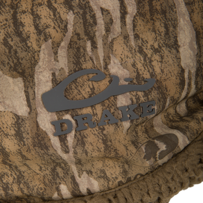 Close-up of Drake's LST BMF Gaiter with Primaloft, featuring camouflage fabric and black logo, designed for warmth, mobility, and weather protection in cold conditions.