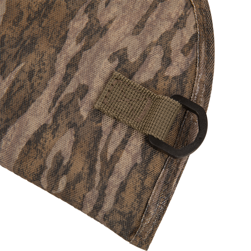 Close-up of The Migrator Gun Case's camouflage fabric with an olive-drab loop and D-ring, highlighting its durable, waterproof design for professional field use.