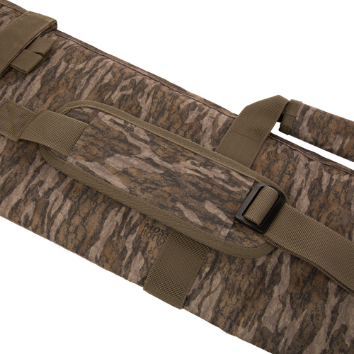 Migrator Gun Case in camo fabric with shoulder strap and handles, featuring durable polyester construction, waterproof PVC backing, and protective EPE foam padding for firearm transport.
