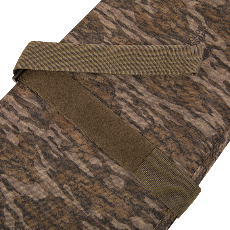 Migrator Gun Case with Mossy Oak camo fabric, olive-drab straps, and Velcro patch, designed for durable, waterproof protection and secure firearm transport.