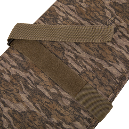 Migrator Gun Case with Mossy Oak camo fabric, olive-drab straps, and Velcro patch, designed for durable, waterproof protection and secure firearm transport.