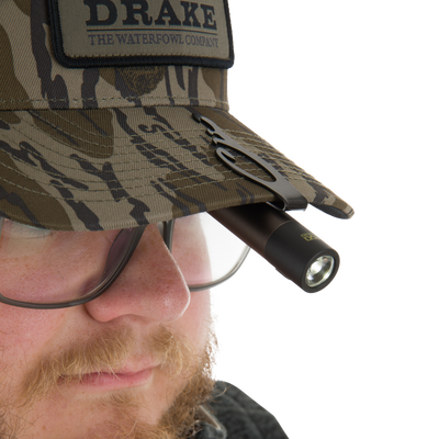 Close-up of a camouflage bucket hat with DRAKE patch, featuring a clipped EVO Cap Light for versatile hands-free illumination.