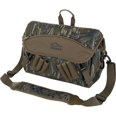 Drake Hardline Shoulder Blind Bag, camo-patterned, with padded strap, external pockets, and shell loops; designed for durable, waterproof gear storage in hunting environments.