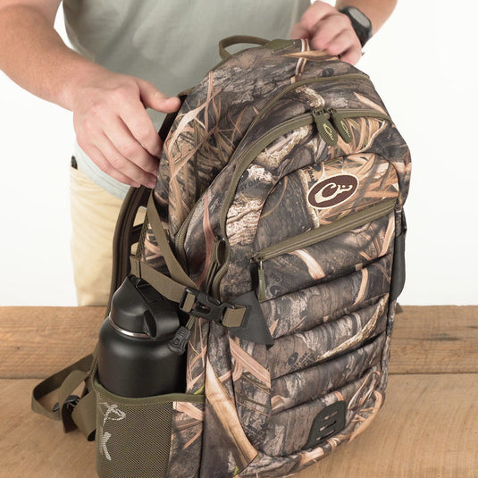 A person holding the Youth Camo Daypack - Mossy Oak Shadow Grass Habitat backpack.