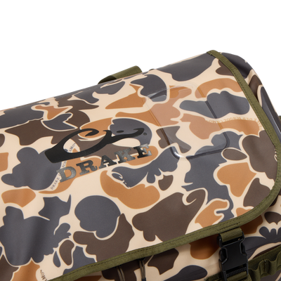 Close-up of a Drake Waterproof Duffel Bag with camouflage pattern, olive-green trim, black buckle, and logo on top flap, featuring durable construction and convenient pockets.